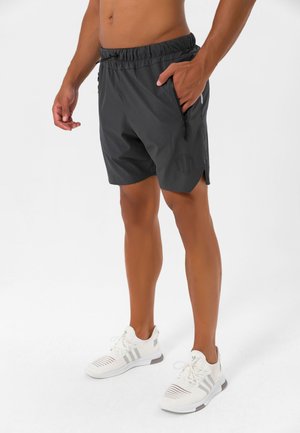 Sorte atletiske shorts med snøre i taljen, sidelommer med lynlås og teksturerede detaljer, med et logo på underbenet.