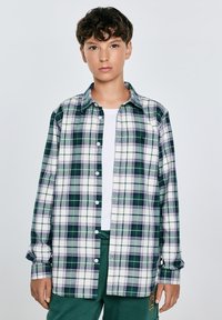 Camicia a maniche lunghe a quadri in verde, blu navy e bianco; tessuto in cotone; vestibilità rilassata; presenta un colletto classico e chiusura con bottoni.