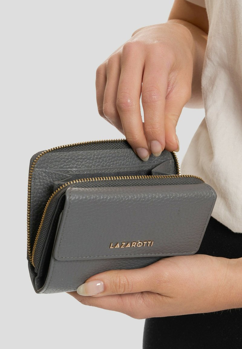 Graue Lederbrieftasche mit goldenem Reißverschluss und Markenlogo. Sie verfügt über ein doppelseitiges Design und wird gehalten, wobei ein offenes Fach sichtbar ist.