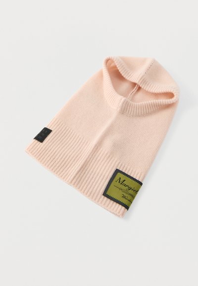 Rózsaszín kötött sapka bordázott mintával, oldalán fekete téglalap alakú címkével, amely zöld díszítéssel és fehér szöveggel rendelkezik.