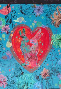 Textil colorido con un diseño de corazón que presenta dos conejos en tonos de rojo y rosa. El fondo incluye motivos florales y de la naturaleza en colores vibrantes.