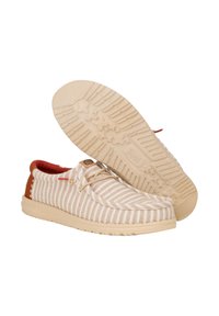 Scarpe slip-on a righe beige e crema, con interno rosso, suola marrone chiaro e accento marrone. Include suola in gomma testurizzata con motivo a stella.