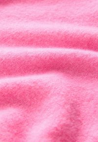 Miękki różowy materiał o teksturowanym wyglądzie, z subtelnymi wariacjami odcieni i gładką, lekko puszystą powierzchnią.