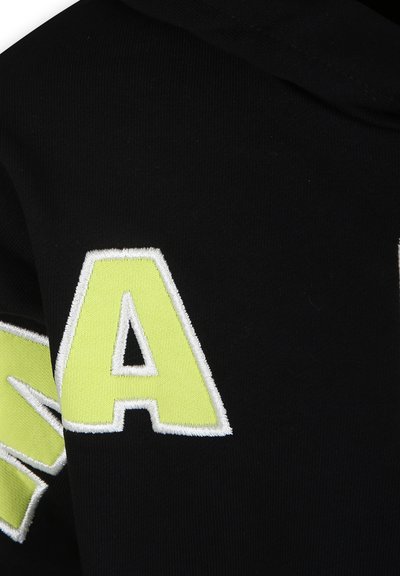 Felpa nera con grandi lettere bianche e neon gialle. Presenta un tessuto morbido e strutturato con cappuccio. Il design include accenti di colore a contrasto.