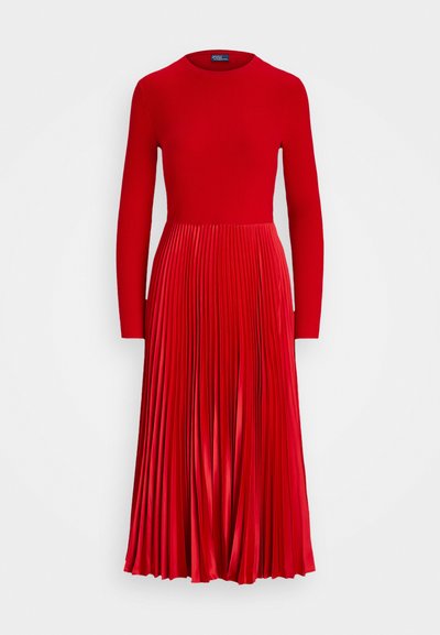 Κόκκινο πλισέ φόρεμα με ριχτό, εφαρμοστό πάνω μέρος, μακριά μανίκια και φουσκωτή φούστα. Φτιαγμένο από λείο, γυαλιστερό ύφασμα με ζωντανό χρώμα.