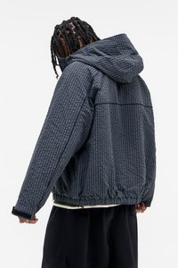 Camisola leve em xadrez preto e cinza com capuz, punhos e bainha elásticos. Tecido texturizado com um corte solto e bolsos com fecho éclair.