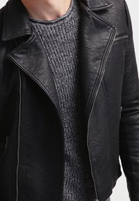 Schwarze Lederbikerjacke mit eingekerbtem Kragen, Reißverschluss vorne und strukturiertem Stoff unten. Verfügt über seitliche Reißverschlüsse und eine passgenaue Silhouette.
