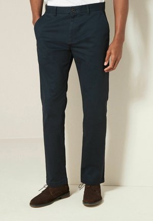 Navyblauwe katoenen broek met een rechte pijp, voorzien van voorzakken, een enkele knoopsluiting en een subtiele textuur.
