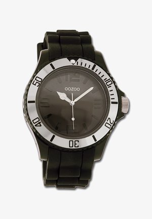 Montre en caoutchouc noir avec un cadran gris rond, une lunette argentée, des marquages horaires proéminents et un bracelet texturé. Dispose d'un affichage de la date à 3 heures.