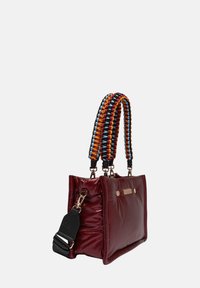 Bordeaux gekleurde gewatteerde tote bag met gevlochten handvatten in meerdere kleuren, metalen hardware en decoratieve stiksels langs de randen. Afneembare schouderband inbegrepen.