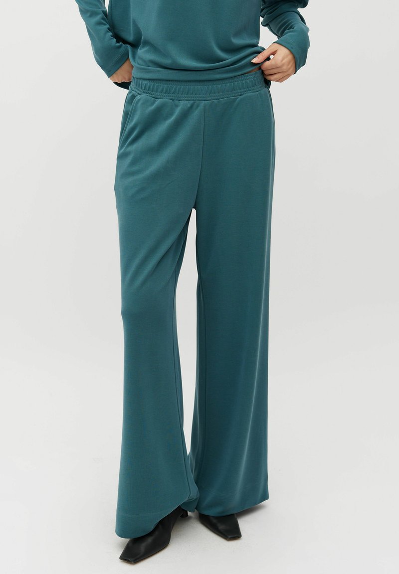 Teal wijde broek in een zachte, textuurstof met een elastische tailleband en zijzakken. Gecombineerd met zwarte schoenen met een puntige neus.