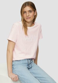 Lichtroze gestreepte t-shirt met korte mouwen en een ronde halslijn. Voorzien van geborduurde tekst "happy" op de voorkant. Gecombineerd met lichtblauwe jeans.