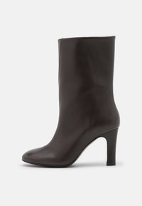 Hög svart läderankelboot med en elegant design, spetsig tå och en måttlig klack. Slät textur och sömlös finish.