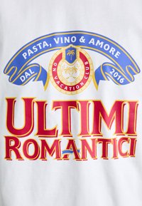 Witte t-shirt met vetgedrukte rode en gele tekst "ULTIMI ROMANTICI," met een blauw lint ontwerp erboven en een cirkelvormig embleem eronder.