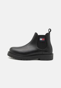 Bottines chelsea en cuir noir avec panneaux élastiques et une languette. Semelle en caoutchouc épaisse avec motif de traction ; comprend un patch logo de marque.