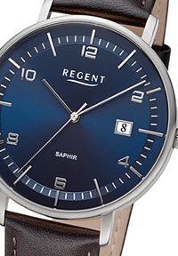 Montre ronde avec un cadran bleu marine, des index horaires en argent et un affichage de la date. Équipée d'un bracelet en cuir marron et d'un boîtier en acier inoxydable.
