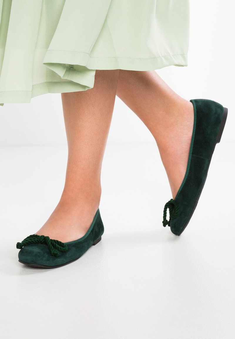 Ballerine in suede verde con finitura testurizzata, dotate di un accento decorativo annodato sulla punta e una suola bassa e piatta.