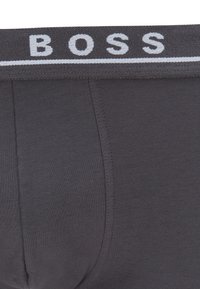 Dunkelgraue Boxershorts mit einem strukturierten Bund, auf dem das Wort "BOSS" in Weiß steht. Glattes Material mit Nähten an den Seiten.