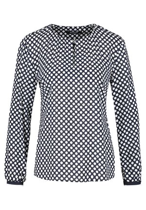 Marineblauwe blouse met lange mouwen en witte polkadots, ronde halslijn en een met knopen afsluitbaar keyhole-detail aan de voorkant in het midden.
