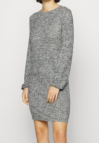 Abito maglione grigio con texture, maniche lunghe, scollatura rotonda e vestibilità comoda. Presenta un motivo intrecciato per un dettaglio in più.