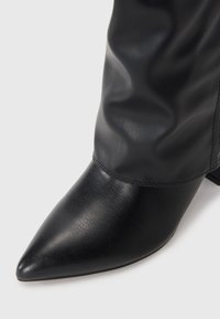 Svarte lær ankle støvler med spiss tå, med en glatt tekstur og en litt slapp skaft. Inkluderer en blokkhelt.