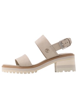 Beige sandal med åben tå, blokhæl, justerbar ankelrem med spænde og Timberland trælogo på side remmen.