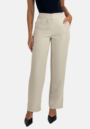 Beige Hosen mit weitem Bein, Knopfverschluss, Fronttaschen, glatter Textur und minimalistischem Design, kombiniert mit schwarzen spitzen Schuhen.