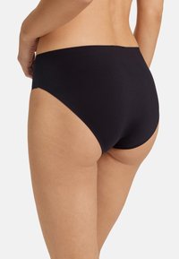 Biancheria intima nera a vita alta realizzata in tessuto morbido e elastico. Presenta un design senza cuciture con cuciture sottili e senza hardware visibile.