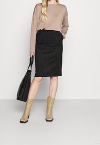 Musta samettinen kynähame, vaalea pitkähihainen paita, vaaleanruskeat nilkkasaappaat ja musta olkalaukku. Yksinkertainen muotoilu istuvalla siluetilla.