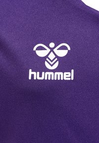 Lilla stof med et hvidt logo, der har stiliserede elementer, herunder runde former og et geometrisk mønster, mærket med "hummel."