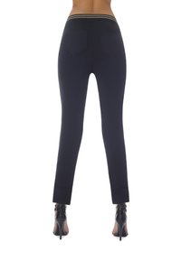 Granatowe legginsy o gładkiej fakturze, z pasem w złote paski i dwiema tylnymi kieszeniami, w połączeniu z czarnymi szpilkami.