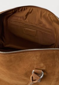 Open bruine suède tas met zichtbare rits, interieur met ritsvak en "PIER ONE" label op de gladde bruine stofvoering.