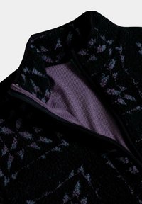 Chaqueta de forro polar con cremallera en negro con un patrón floral púrpura. Presenta un cuello alto y forro de malla para mayor transpirabilidad. Tejido texturizado.