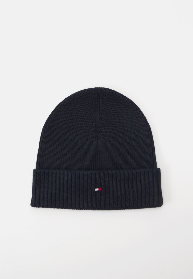 Bonnet en tricot bleu marine avec un revers côtelé, arborant un petit logo rouge, blanc et bleu. Texture lisse et matériau extensible pour un bon ajustement.