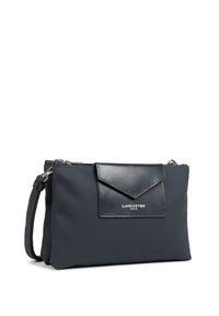 Borsa a mano blu navy realizzata in materiale sintetico testurizzato. Presenta una elegante patta frontale con un accento liscio e hardware in metallo. Logo del marchio in evidenza.