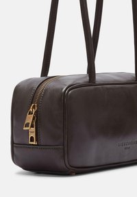 Braune Lederhandtasche in rechteckiger Form, mit einem goldenen Reißverschluss, zwei Griffen und geprägtem Markennamen auf der Seite.