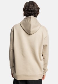 Beige hoodie met een zachte textuur, voorzien van een ontspannen pasvorm, geribde manchetten en een eenvoudig, onopgemaakt ontwerp.