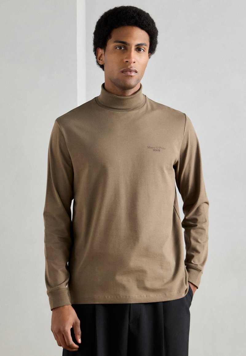 Pruun pikkade varrukatega kõrgekaelusega särk pehmest kangast, selge lõikega. Rinnal on peen logo ja soonikkäised.