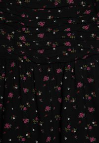 Vestido floral preto com detalhes franzidos. Pequenas flores rosas e brancas espalhadas pelo tecido. Material suave e texturizado.