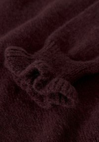 Burgundowy sweter z dzianiny o miękkiej fakturze, z prążkowanymi mankietami i zawiniętymi brzegami, co nadaje mu przytulny wygląd.