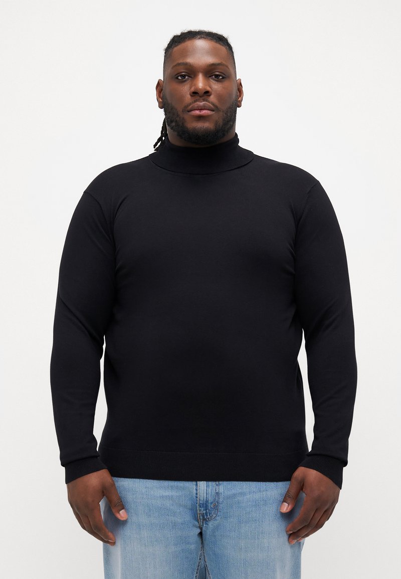 Pulover negru cu guler înalt și mâneci lungi, fabricat dintr-un material neted. Prezintă un design ajustat și manșete și tiv cu dungi. Purtați cu blugi de culoare albastru deschis.