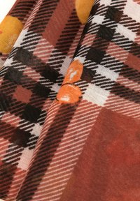 Écharpe multicolore avec un motif tartan présentant des teintes de marron, noir et orange ; texture douce et tissu léger.