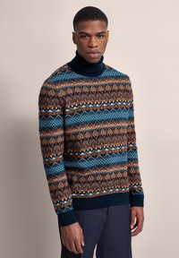 Pullover mit einem Rollkragen-Design, aus strukturiertem Strickmaterial gefertigt. Er zeigt ein geometrisches Muster in den Farben Braun, Blau und Creme.