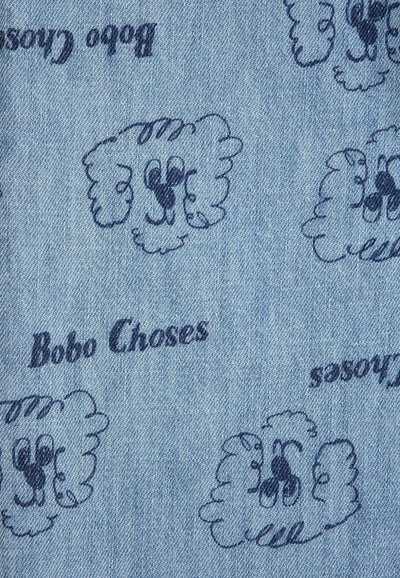 Tissu en denim bleu imprimé de visages de chiens de dessin animé bleu marine répétés et du texte "Bobo Choses" dans des orientations variées.