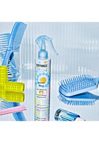 Spray rafraîchissant Amika Power Hour pour boucles dans un flacon transparent avec un motif floral coloré. Entouré de peignes bleus, de rouleaux jaunes et d'une brosse bleue.