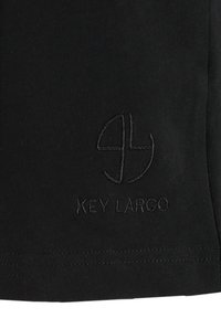 Schwarzes Stoff-T-Shirt mit einem dezenten gestickten Logo mit "KEY LARGO" darunter. Glatte Textur, klassischer Rundhalsausschnitt und kurze Ärmel.