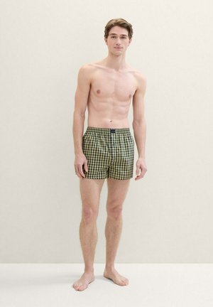 Männliche karierte Shorts in Grün und Schwarz, mit einem elastischen Bund und einer lockeren Passform. Der Stoff wirkt leicht und hat eine glatte Textur.
