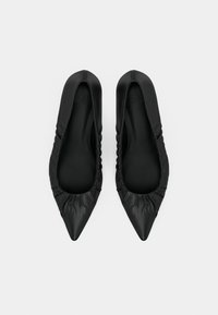 Mustad satiinsed libisevad madalad kingad teravate ninaosadega, voltidega ääres ja sileda sisevoodriga.