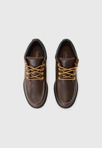 Bruine leren schoenen met gele veters, een ronde teenvorm, witte stiksels en een zwarte rubberen zool. Beschikt over een waterdicht ontwerp.