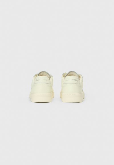 Krémové kožené tenisky s textúrovaným povrchom, so zjemnenými goliermi a mäkkou podrážkou. Branding "Filling Pieces" na päte.